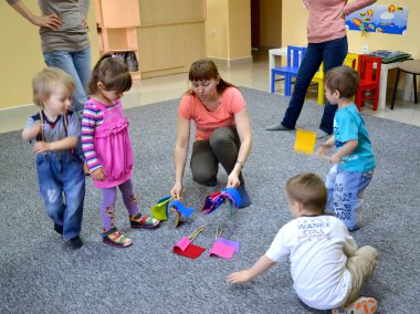 KALININGRAD, RUSSIA - APRIL 17, 2014: The tutor distributes to children color tags for occupation. Studio of creative development