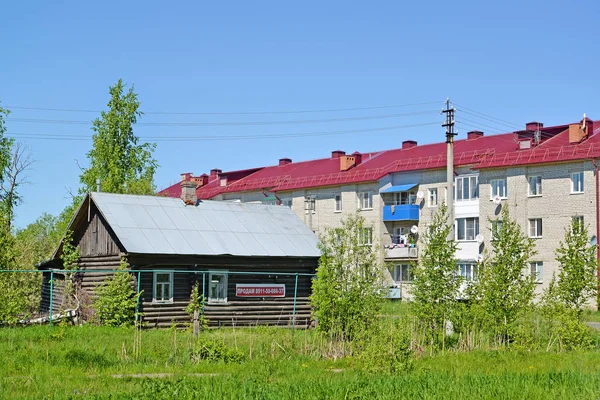 POSHEKHONJE, RUSSIA - 28 MAGGIO 2018: La vecchia casa in legno con l'annuncio della vendita sullo sfondo dell'edificio in mattoni appartamento — Foto Stock