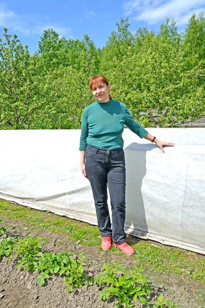 The woman of average years stands near a hotbed — Stock Photo, Image