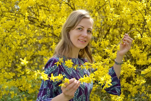The thirty-year-old woman admires flowers of a forsythia. Portrait — Stock Photo, Image