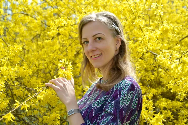 Portrait de la jeune femme sur fond de couleurs jaunes d'une forsythie — Photo
