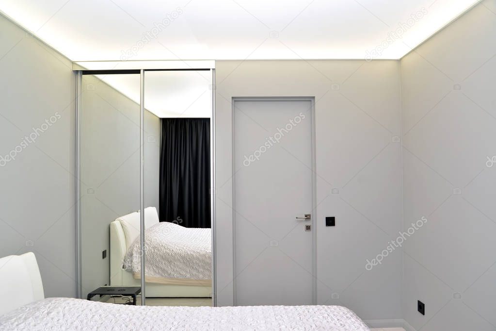 The modern bedroom with mirror sliding wardrobe