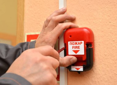 Adam yangın uyarısı düğmesine bir oda duvara bağlanır. Rus metni, ateş. Aşağı Shift