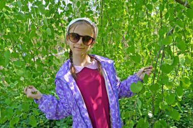 Yaprakları ile dalları arka plan karşı yedi yaşındaki kız