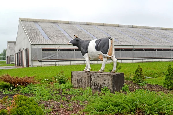 Cow sculpture against the background of buildings of a livestock complex