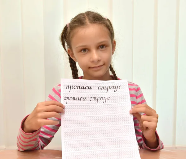 这个女孩展示了一本有文字的抄本本的叶子。俄语文本 - 抄本本，驼鸟 — 图库照片