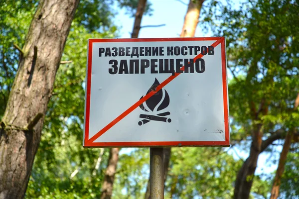 Die Verbotstafel "Anbau von Feuer ist verboten" vor dem Hintergrund von Bäumen im Park. russischer Text — Stockfoto
