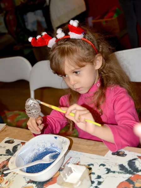 A left-handed girl paints a tree toy. Children 's master class in the workshop — Stock Photo, Image