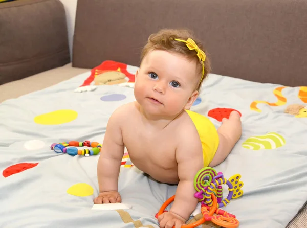 Bebé con juguetes yace sobre su estómago, descansando sobre sus manos — Foto de Stock