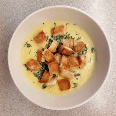 Kabak kremalı çorba, kızarmış ekmek ve otlar.