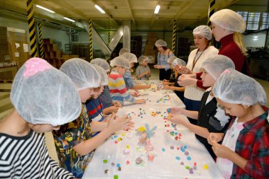 Kaliningrad, Rusya - 27 Eylül 2019: Şekerleme mastiğinden figürlerin pastası üzerinde çocuk ve ebeveynlerin müşterek işgali. Çikolata faktörü üzerine çocuk master sınıfı.