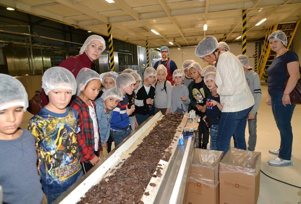 KALININGRAD, RUSSIA - SEPTEMBER 27, 2019: Schoolchildren look at the operation of a transport belt with pebble chocolate. Children s tour to the chocolate factory BELGOSTAR — Stock Photo, Image