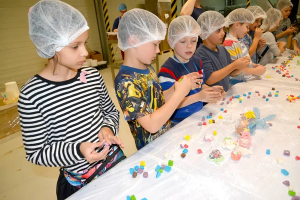 Калінінград, Росія - 27 вересня 2019: школярі займаються витягуванням фігур з кондитерських мастил. Дитячий майстер на шоколадній фабриці. — стокове фото