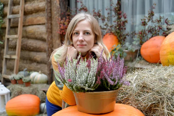 Retrato de una mujer con Heather sobre un fondo de calabazas naranjas. Cosecha de otoño — Foto de Stock