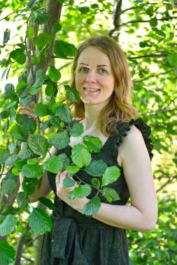 Yeşil yaprakların arasında genç bir kadının portresi