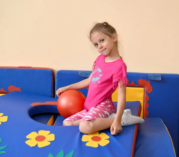 Una Niña Pequeña Sienta Con Una Pelota Una Colchoneta Gimnasia —  Fotos de Stock