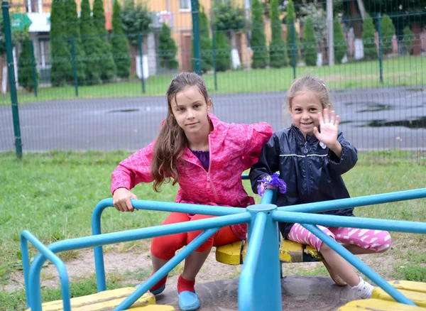 两个女孩坐在一个旋转木马上 游乐场地 — 图库照片