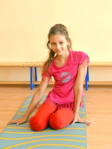 一个10岁的女孩坐在体育馆的体操垫子上 — 图库照片