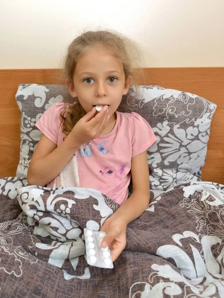 Una Niña Cinco Años Pone Una Pastilla Boca Mientras Está — Foto de Stock