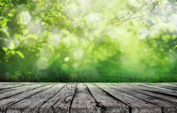 木製のテーブルと春の草や木の葉背景 — ストック写真