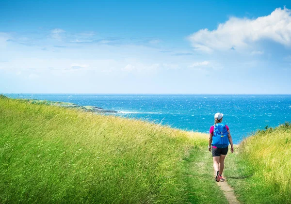 Girl with backpack travels along sea coast along Camino de Santi — Stock Photo, Image