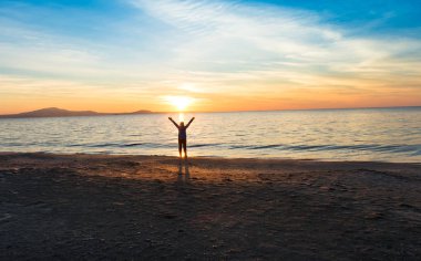 gün batımında denize yakın kız silueti