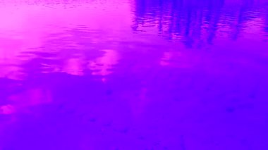 Suda dalgalanmalar ve dalgalar. Yansımış bulutlar. Mor ve mavi renkli renkler. Video küçük resim.