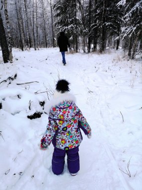 küçük bir çocuk kış ormanında yürüyor