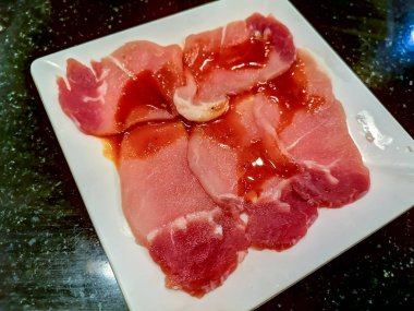 Beyaz tabak üzerinde çiğ çiğ domuz dilimlenmiş