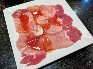 Beyaz tabak üzerinde çiğ çiğ domuz dilimlenmiş