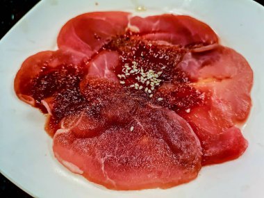 Beyaz tabak üzerinde çiğ çiğ domuz dilimlenmiş