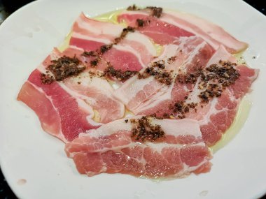 Beyaz tabak üzerinde çiğ çiğ domuz dilimlenmiş