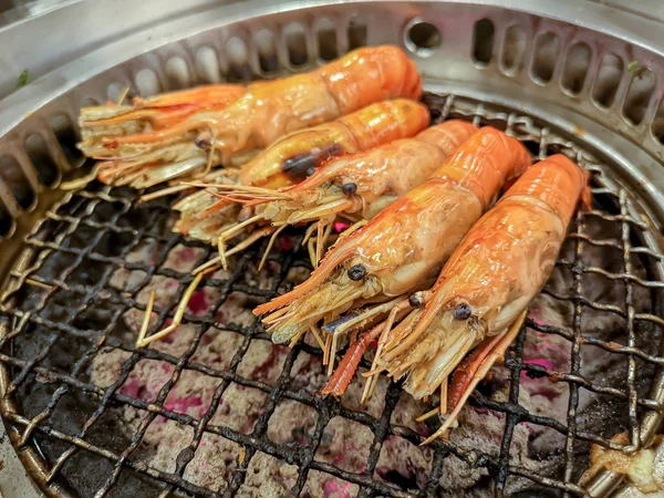 Cooking by grilling prawn on charcoal barbecue stove