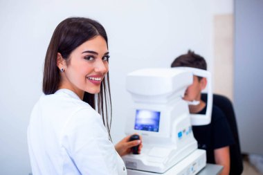 Kadın okulist klinikte göz görme kontrol etmek için makine kullanarak. Küçük çocuk ekipman ve optik mağazada Doktor test göz öğrenciye bakıyor. Göz bakımı ve sağlık konsepti.