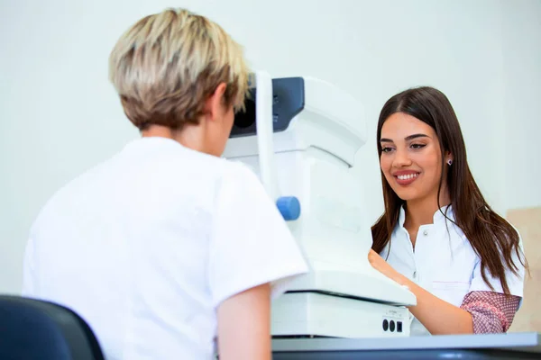女性医師眼科医は、現代の診療所で魅力的な若い女性の視力をチェックしています。眼科クリニックの医師と患者. — ストック写真