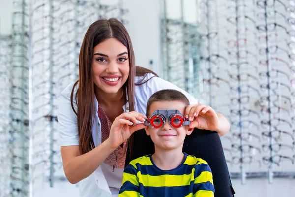 Optometrist deneme çerçevesi ile youg çocuk inceleyerek çekici Oftalmolog. Çocuk hasta Oftalmolojik klinikte vizyonu kontrol etmek — Stok fotoğraf