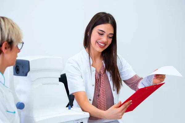 female ophthalmologist showing patient\'s data to a clipboard, working in an optical store. Healthcare and medicine concept