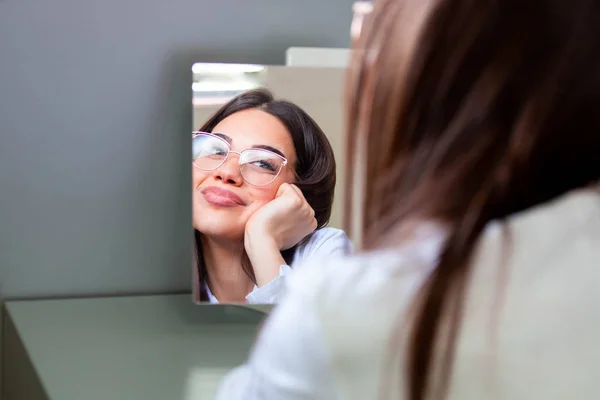 鏡の前で眼鏡をかけてる若い女の子。視力の向上に役立ち、目の健康を救う — ストック写真