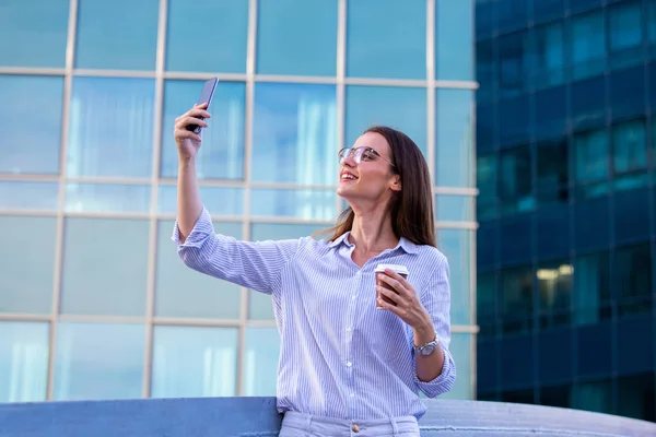 Executive business woman looking at mobile smartphone and drinki