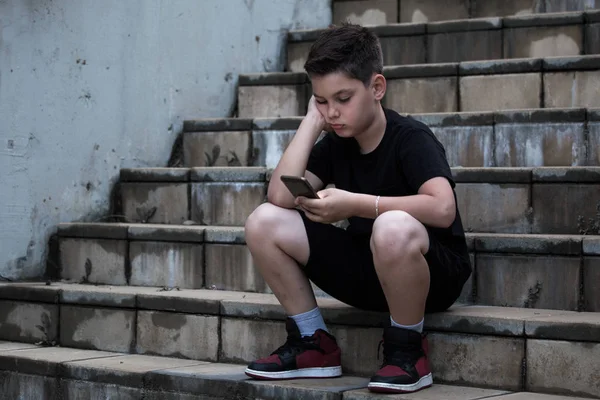 Triste garçon regardant téléphone portable avec la main sur la tête — Photo