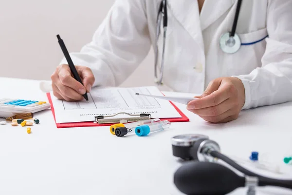 Docteur femme remplissant le formulaire de prescription alors qu'elle était assise au bureau en gros plan de l'hôpital. Médecin au travail et prêt à donner un conseil pour aider le patient. Soins de santé, assurance et excellent service dans — Photo