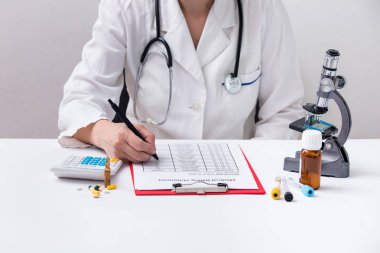 Doktor kadın hastane yakın çekim masasında otururken reçete formu dolduruyor. Doktor iş yerinde ve hasta yardım için bir tavsiye vermeye hazır. Sağlık, sigorta ve mükemmel hizmet 