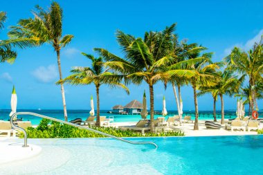 Lhaviyani Atoll, Maldives - 13 Temmuz 2018: havuzda şezlong ve şemsiyeler palmiye ağaçları gölgesinde ile Hint Okyanusu kıyısında alanı