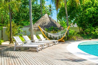 Lhaviyani Atoll, Maldives - 13 Temmuz 2018: havuzda şezlong ve şemsiyeler palmiye ağaçları gölgesinde ile Hint Okyanusu kıyısında alanı