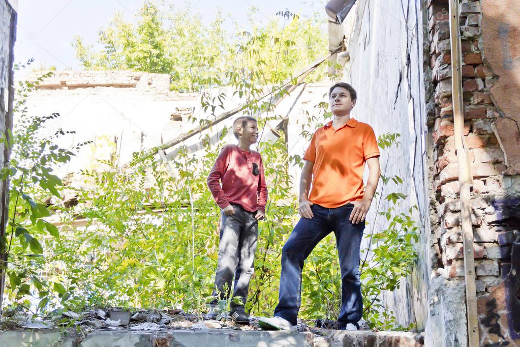 Father and teenager son are standing in ruins