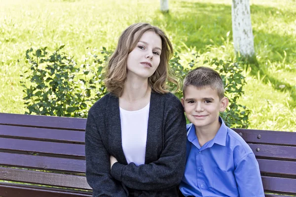 哥哥和妹妹夏天坐在长凳上 — 图库照片