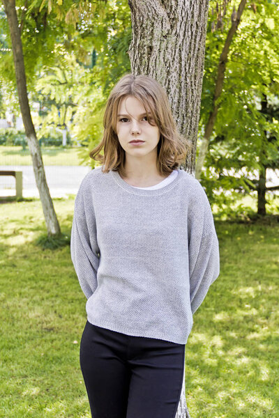 Beautiful girl fourteen years old lean on the tree