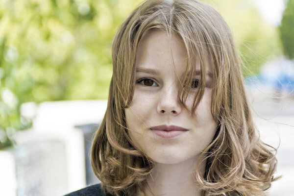 Cute blond girl fourteen years old in summer background