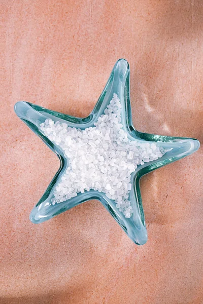 玫瑰大理石板上有蓝色玻璃海星的海盐片 — 图库照片