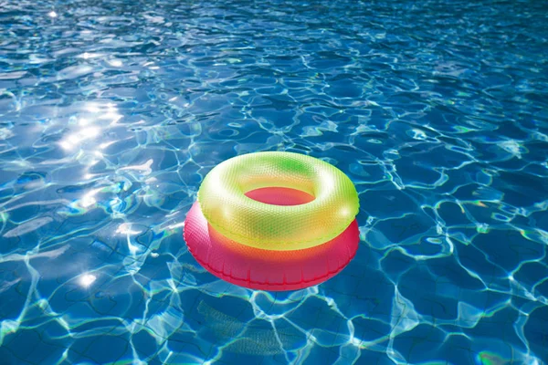 在夏日阳光中反射的波浪在蓝色水 Swimpool 上漂浮的圆环 — 图库照片